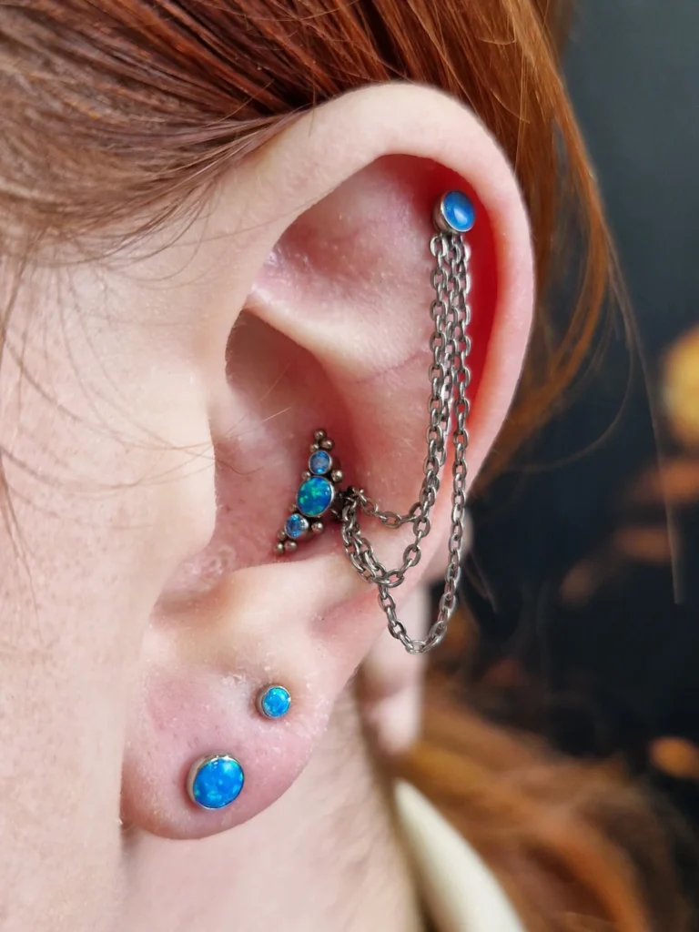 Piercingy v uchu, helix, conch, lalůček je propojený řetízkem